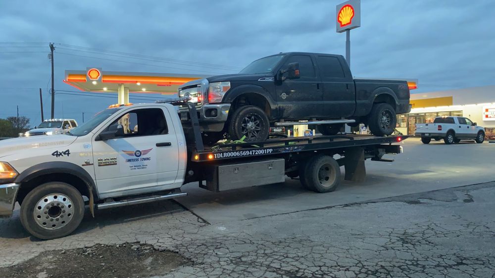 A truck with a flat bed is parked in front of a gas station