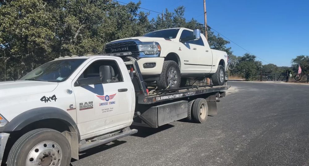 A white tow truck with a flat bed on the back of it